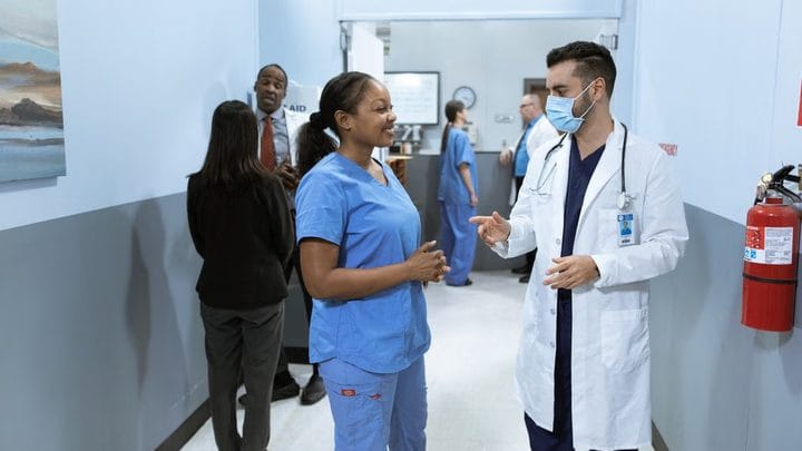 A nurse and a doctor talking in a hospital hallway